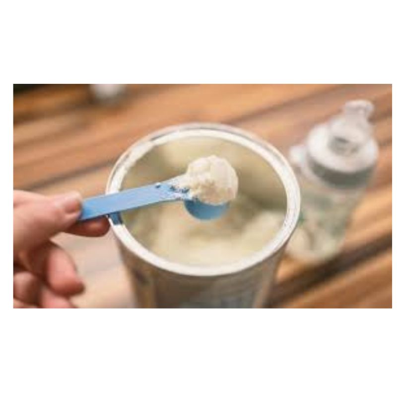 Colher com leite em pó e copo de leite